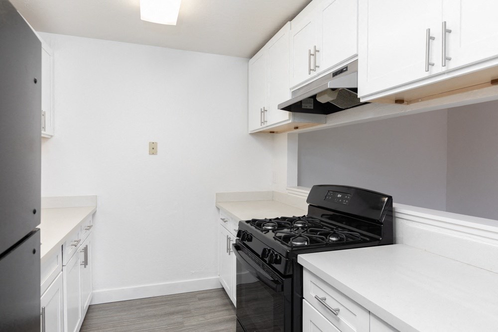 an empty kitchen with white cabinets and a black stove