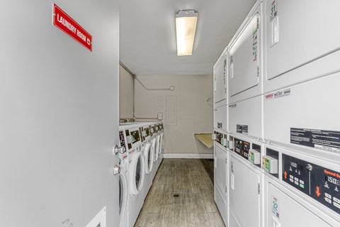 A laundry room with washing machines and a red sign on the wall.