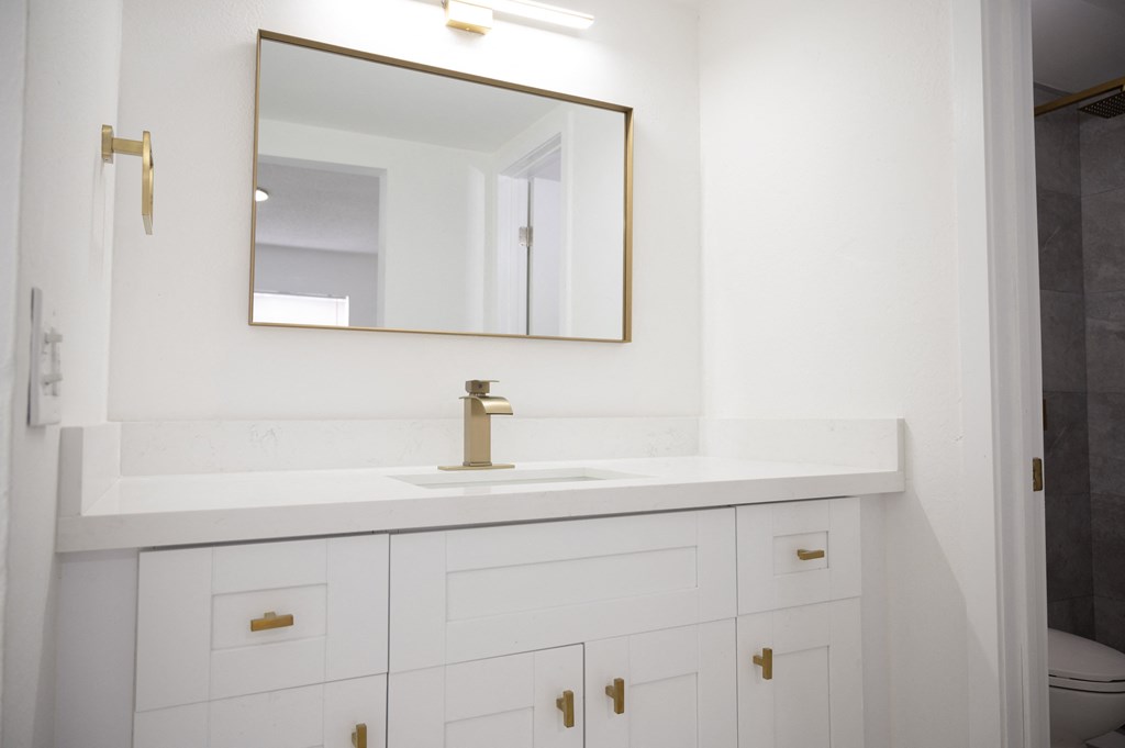 a bathroom with white cabinets and a sink and a mirror