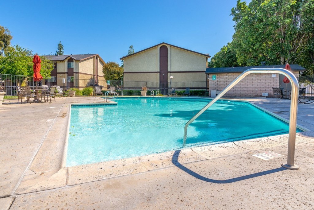 A swimming pool with a diving board in the foreground and a building in the background.