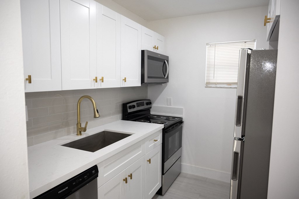 a kitchen with white cabinets and black appliances and a stainless steel refrigerator