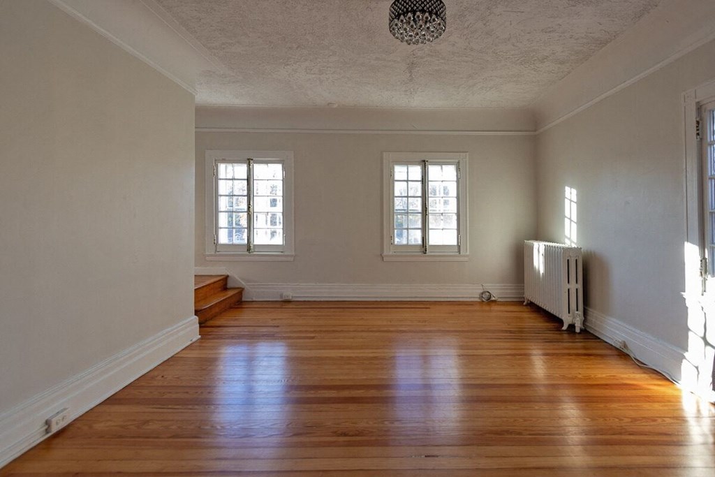 an empty living room with a hard wood floor and two windows