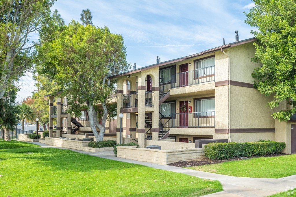 Apartment building with green trees and bushes in front.