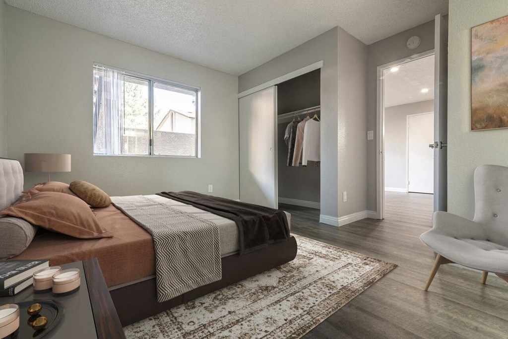 A bedroom with a large bed and a chair.