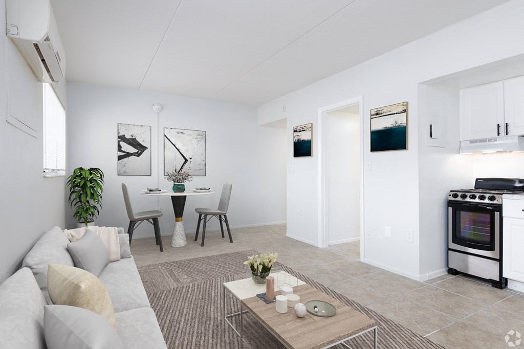 a living room with a couch a table and two chairs and a kitchen with a stove and