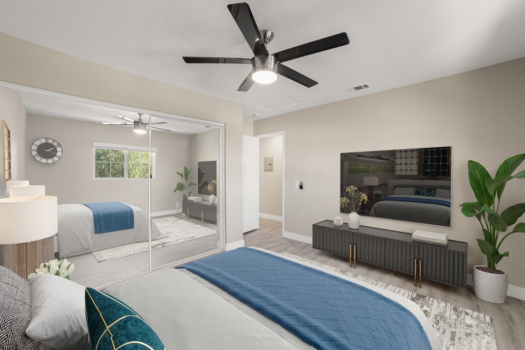 A bedroom with a bed, a ceiling fan, and a television.