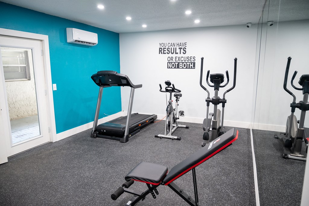 a gym with treadmills and exercise equipment in a room with a blue wall