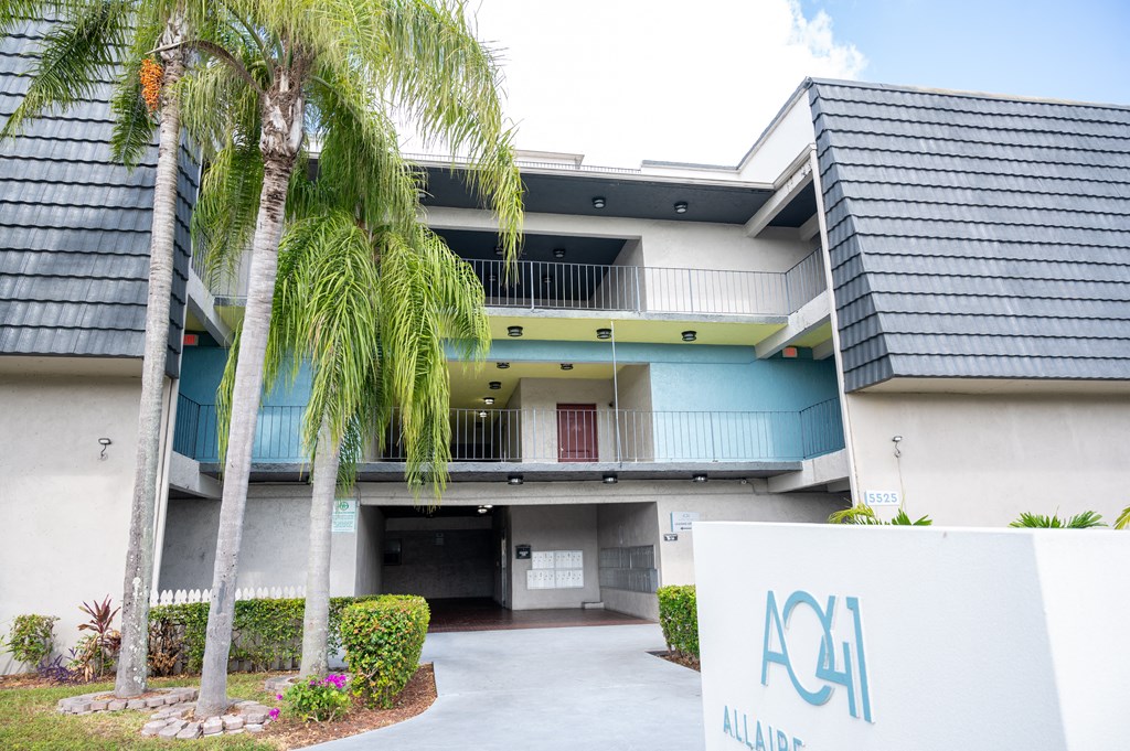 the entrance to a building with palm trees in front of it