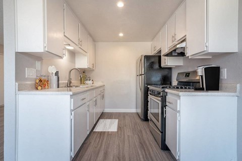 a white kitchen with stainless steel appliances and white cabinets