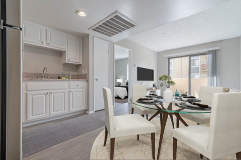 a dining room and kitchen with white cabinets and a table