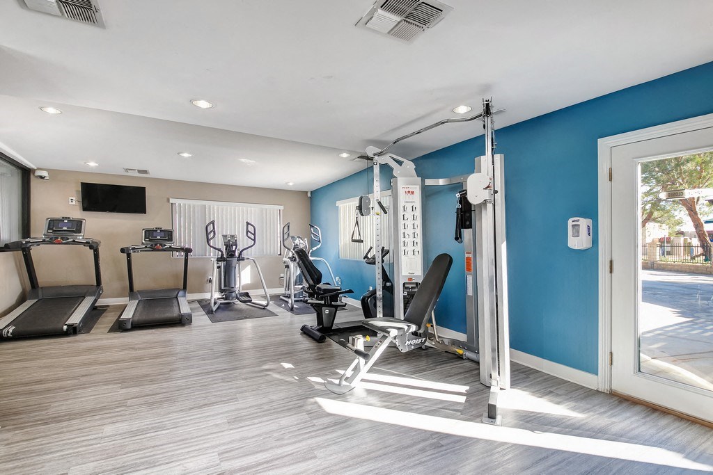 a gym with cardio equipment and a window overlooking a pool