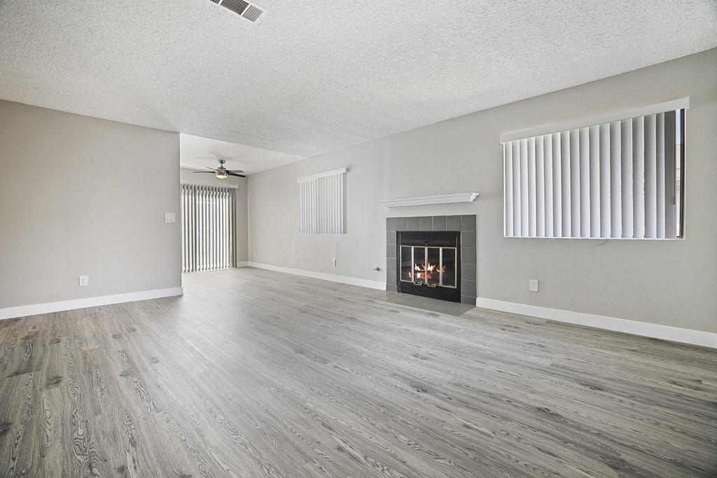 A spacious room with a fireplace and wood flooring.