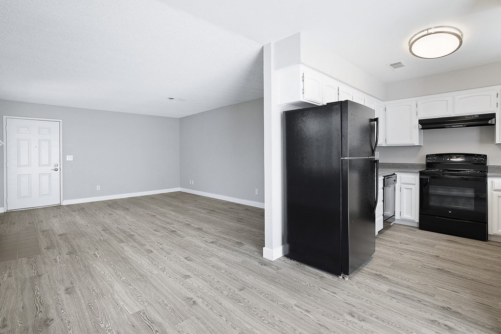 A kitchen with a black fridge and wooden floors.