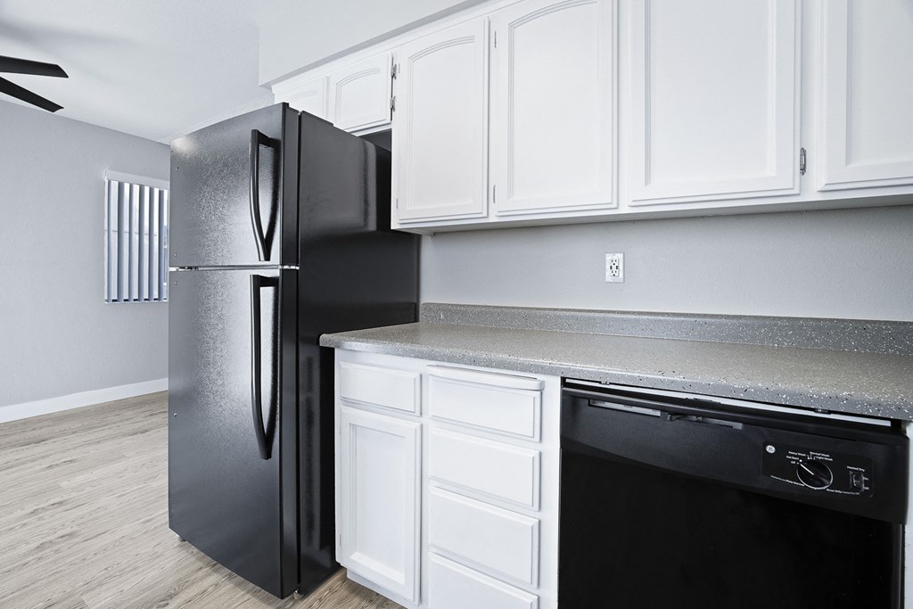 A black refrigerator stands next to a white oven in a kitchen.