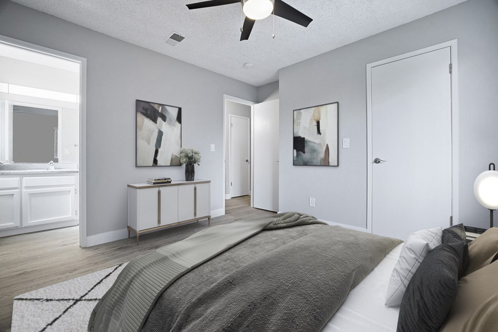 A bedroom with a bed, a ceiling fan, and two framed pictures on the wall.
