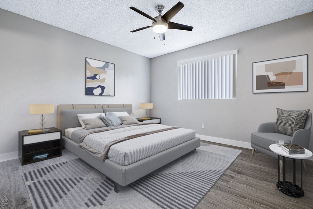 A bedroom with a large bed, a ceiling fan, and a chair.