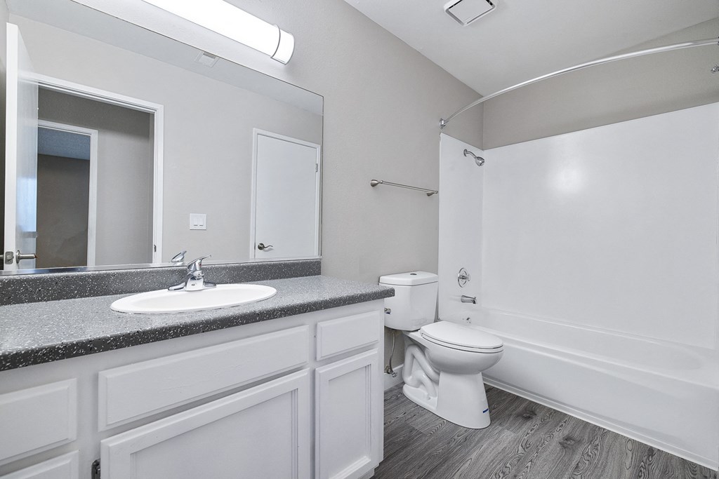 A bathroom with a toilet, sink, and mirror.