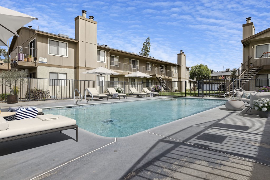A swimming pool surrounded by a fence and chairs.