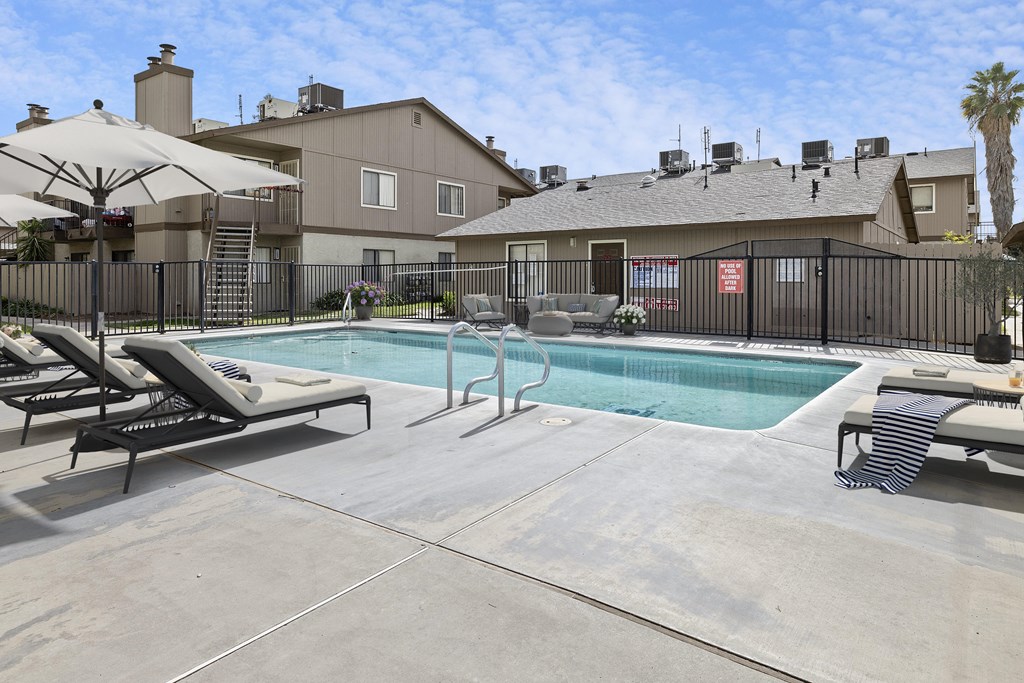 A pool area with sun loungers and a building in the background.