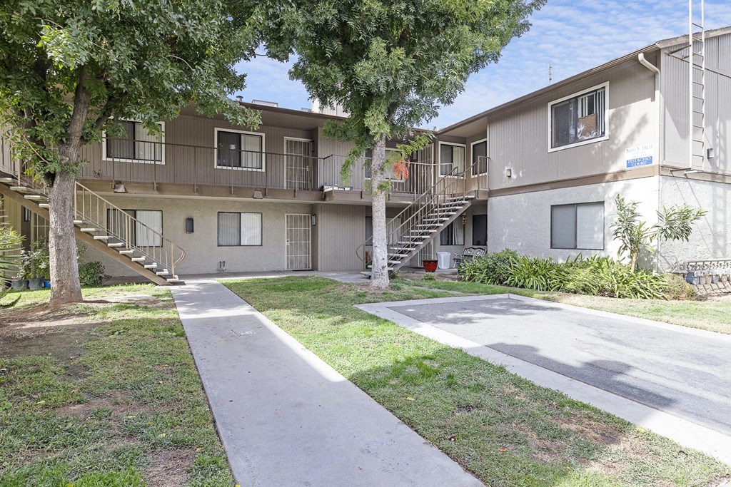 an exterior view of an apartment building with sidewalks and trees
