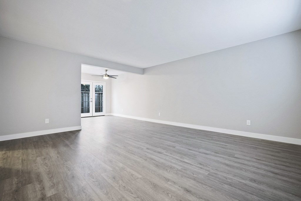 an empty living room with white walls and wood floors