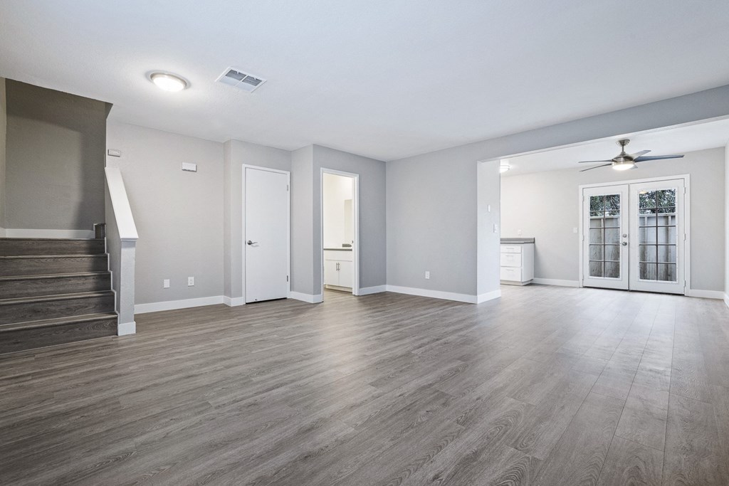 the living room and entryway of an empty house with white walls and wood floors