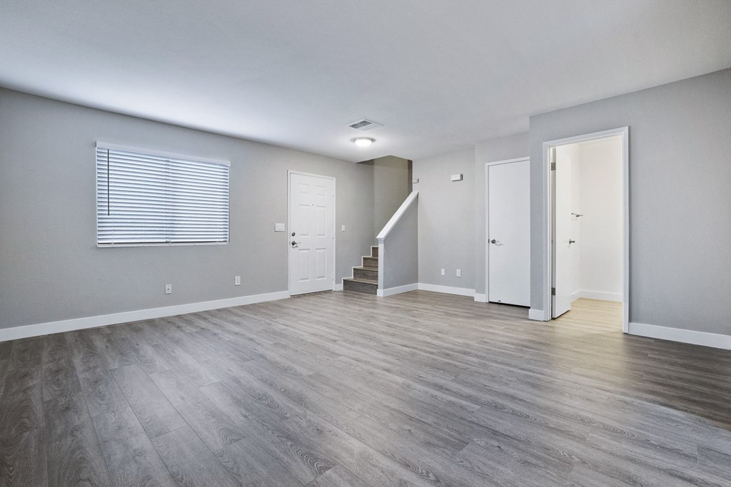 an empty living room with hardwood flooring and a staircase