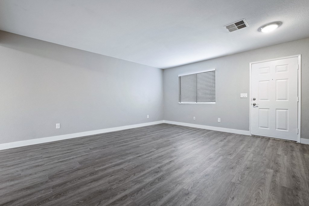 an empty living room with wood floors and a white door