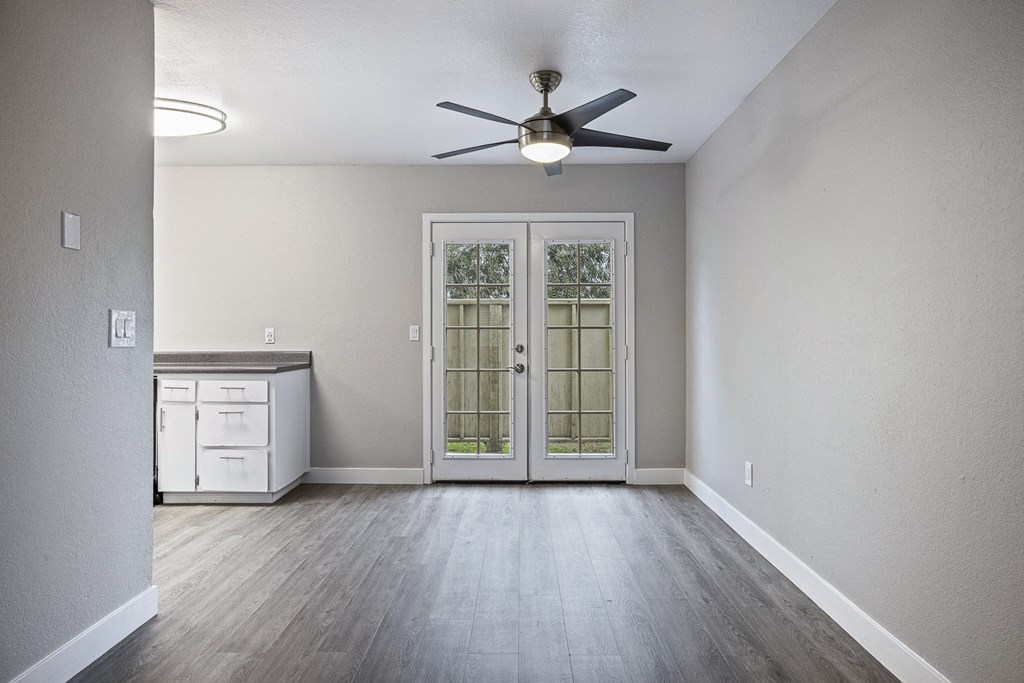 an empty living room with a ceiling fan and a kitchen