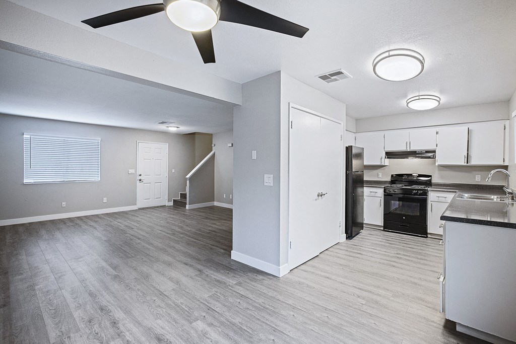 an empty kitchen and living room with a ceiling fan