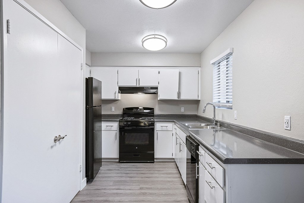 an empty kitchen with white cabinets and black appliances