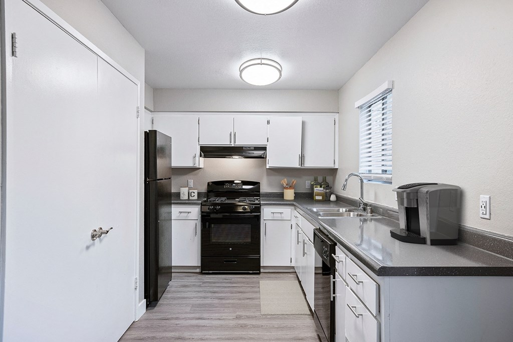 an empty kitchen with white cabinets and black appliances