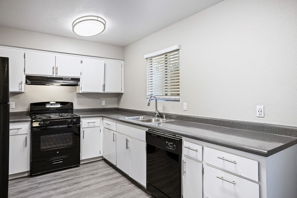 an empty kitchen with white cabinets and black appliances