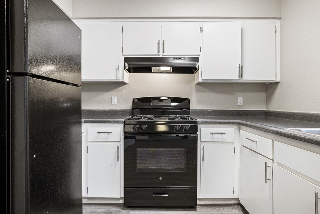 an empty kitchen with white cabinets and a black stove and refrigerator