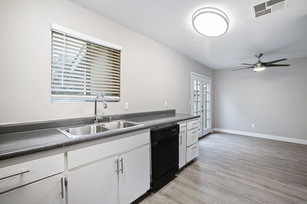 an empty kitchen with a sink and a ceiling fan