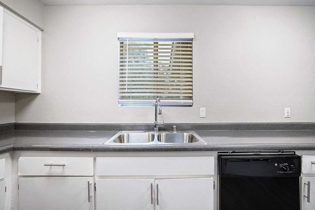a kitchen with white cabinets and a sink and a window