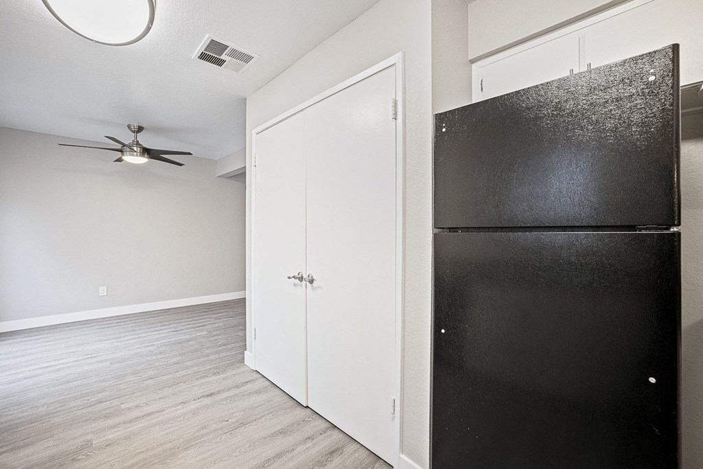 an empty room with a refrigerator and a ceiling fan