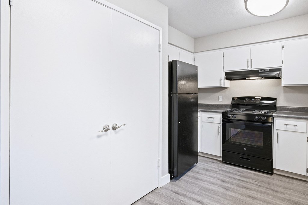 an empty kitchen with white cabinets and a black refrigerator