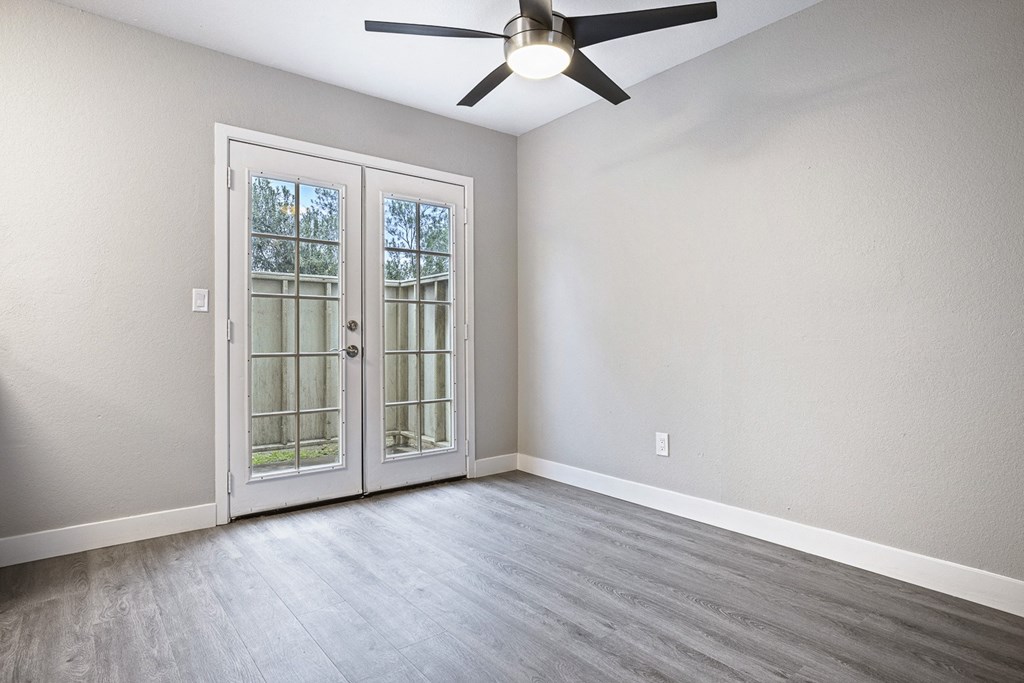 an empty living room with a ceiling fan and glass doors