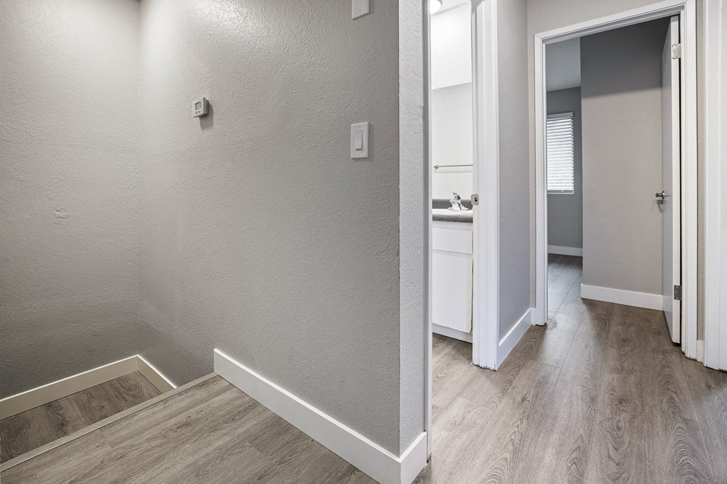 an empty room with a hallway to a bathroom and a sink