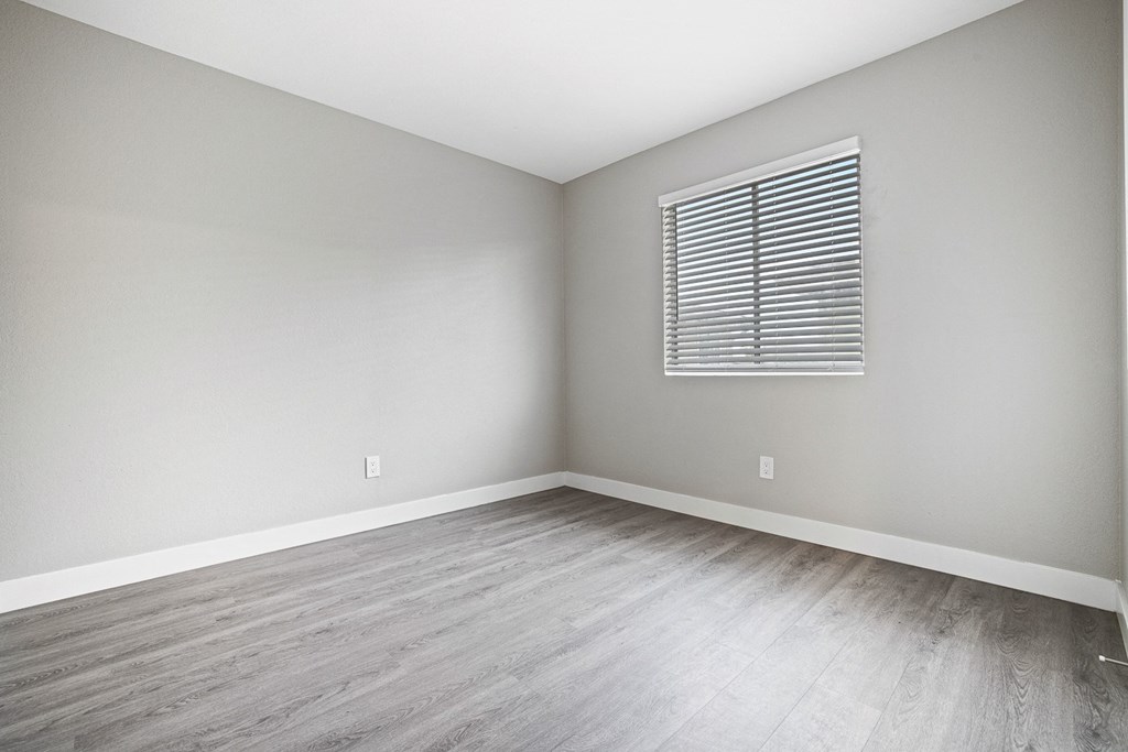 an empty room with wood floors and a window