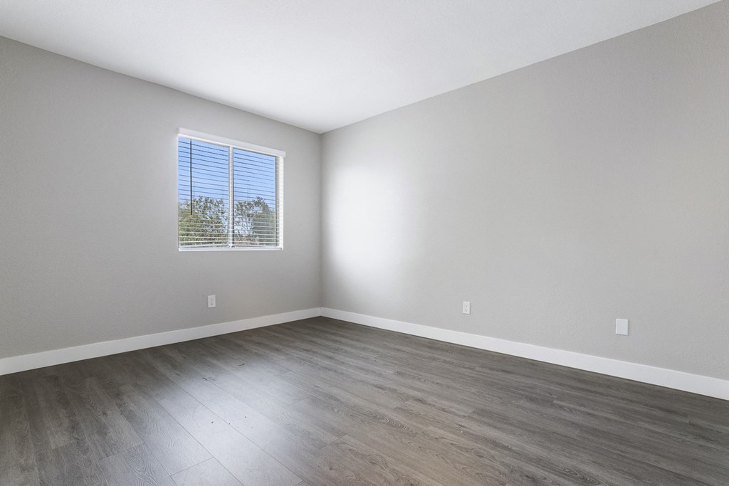 an empty room with wood floors and a window
