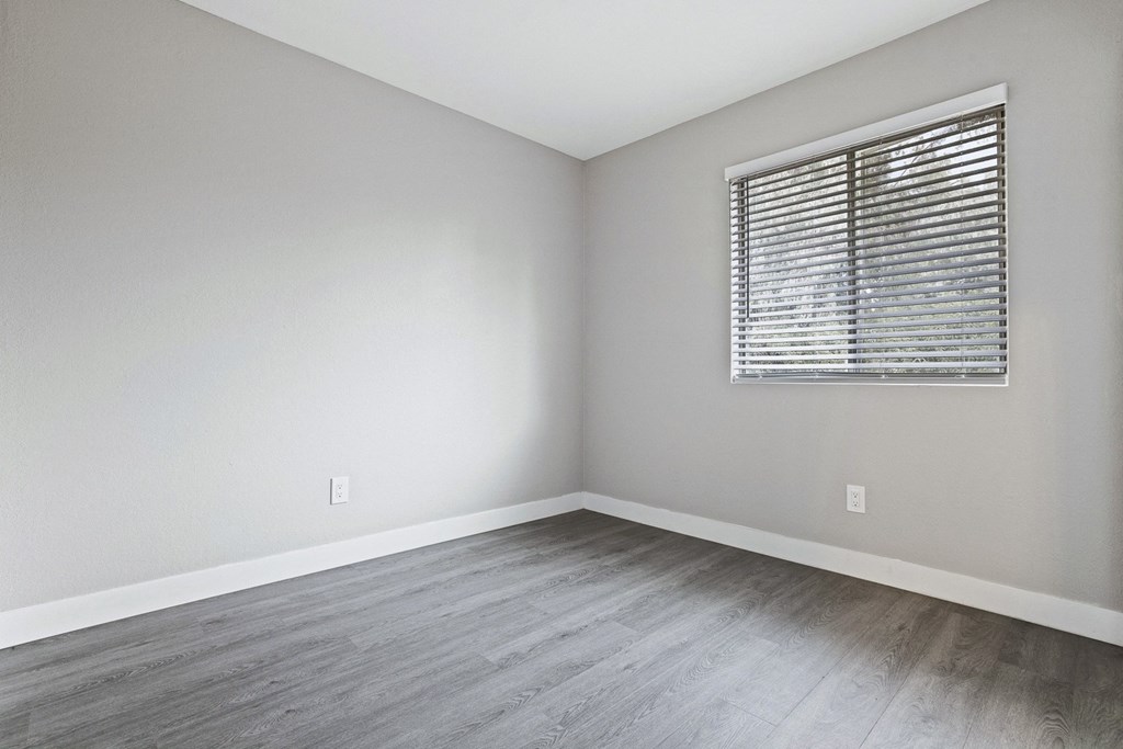 an empty room with wood floors and a window