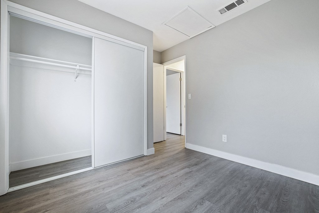 an empty room with white walls and wood floors and a closet