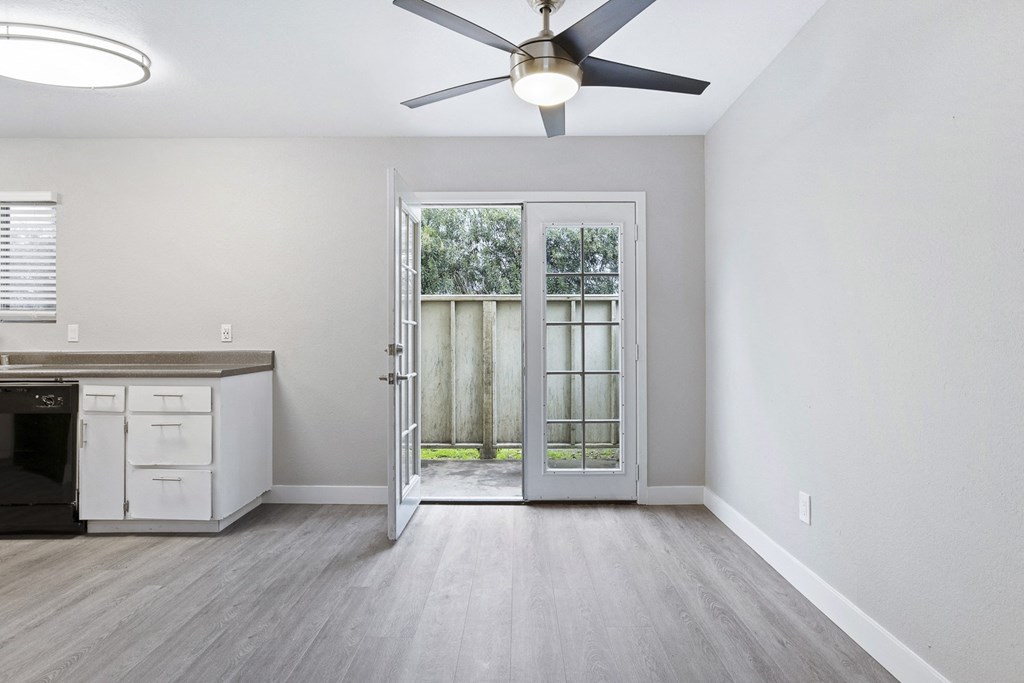 an empty living room with a ceiling fan and a door to a patio