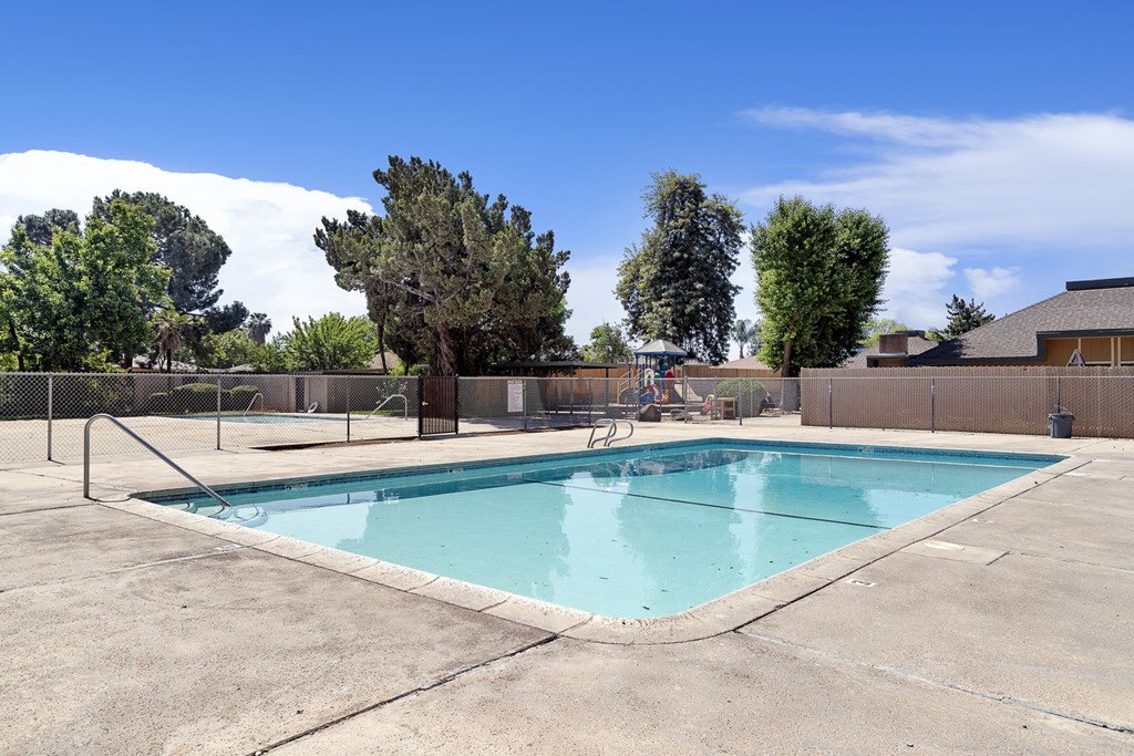 a swimming pool with a fence around it and a house in the background
