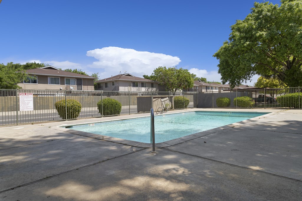 a swimming pool in a fenced in yard with houses in the background