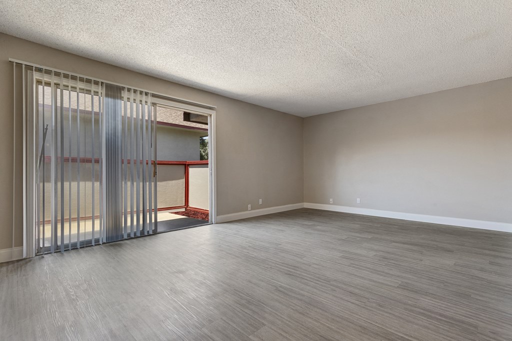 an empty living room with sliding glass doors to a patio