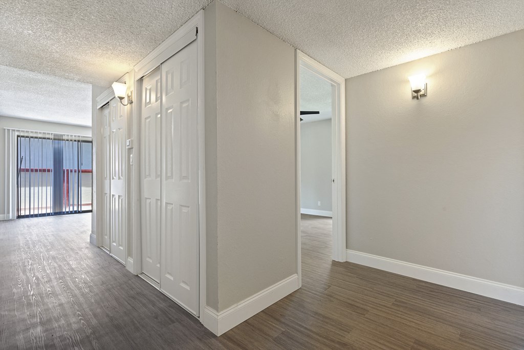 an empty living room and hallway with white walls and wood flooring