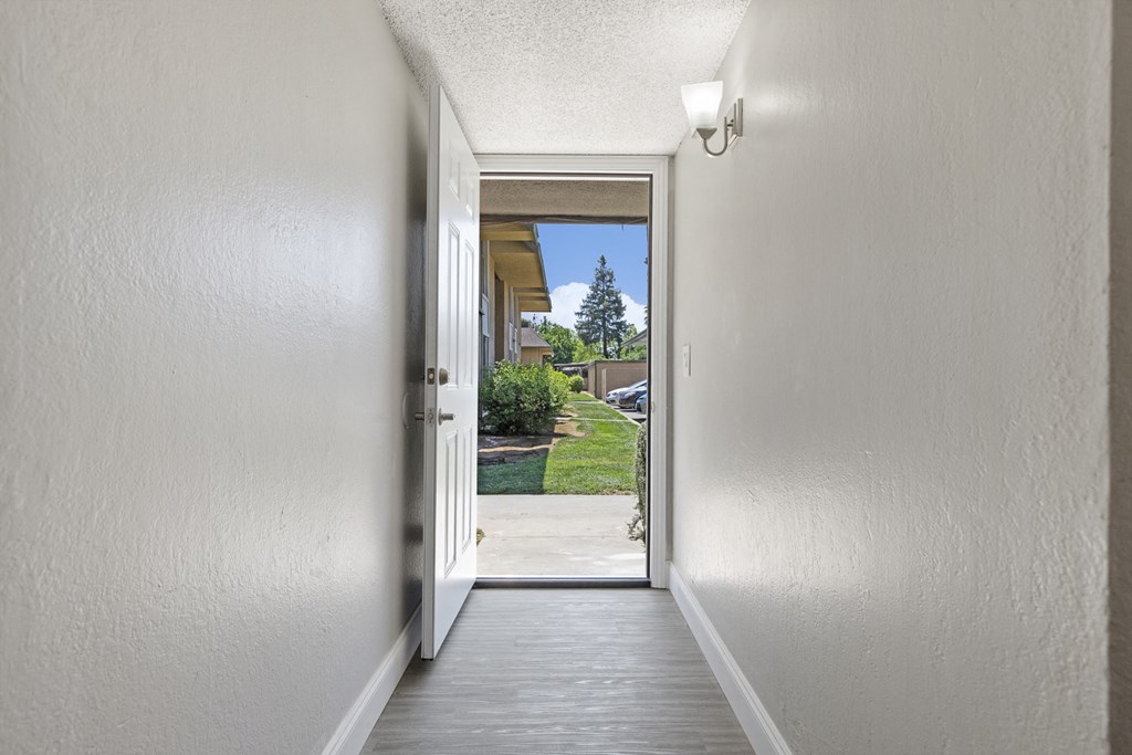 a hallway with a door open and a view of a yard and a house